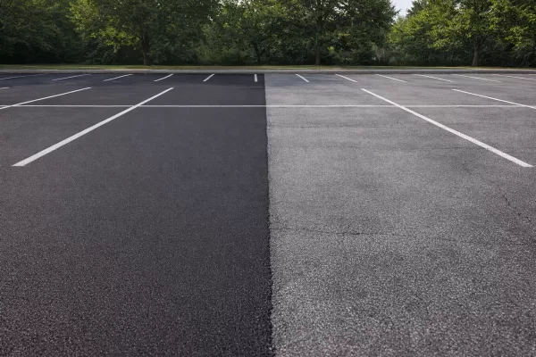 Illustration of a commercial asphalt surface with areas showing protection and fading, no people or vehicles.