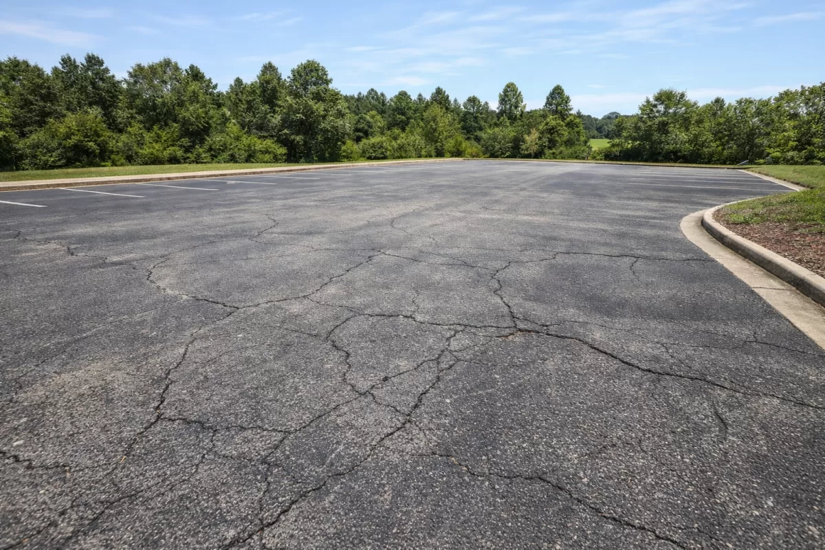 Illustration of a faded and cracked commercial asphalt lot under sunny conditions, no people or vehicles present