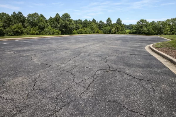 Illustration of a faded and cracked commercial asphalt lot under sunny conditions, no people or vehicles present