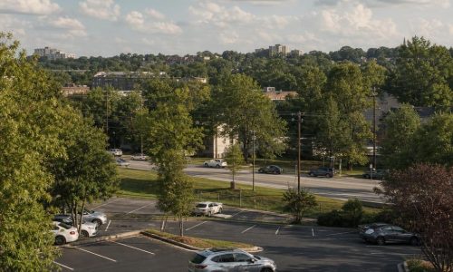 Atlanta parking lot on a gentle, tree-lined urban slope with lush greenery; no signs or logos.