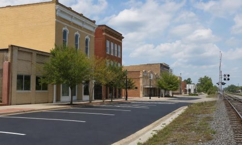 Low-rise historic downtown Douglas streetscape beside a paved lot near a railroad corridor.