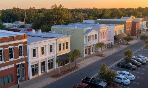 Monticello, Florida streetscape with intact low-rise historic façades and an unlettered asphalt parking area.