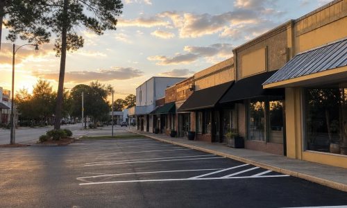 Freshly striped asphalt lot beside modest low-rise storefronts in a small North Florida town.