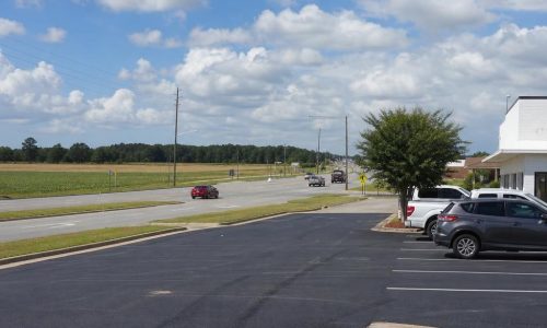 Freshly striped asphalt lot beside a broad Tifton, Georgia roadside with open South Georgia fields beyond.